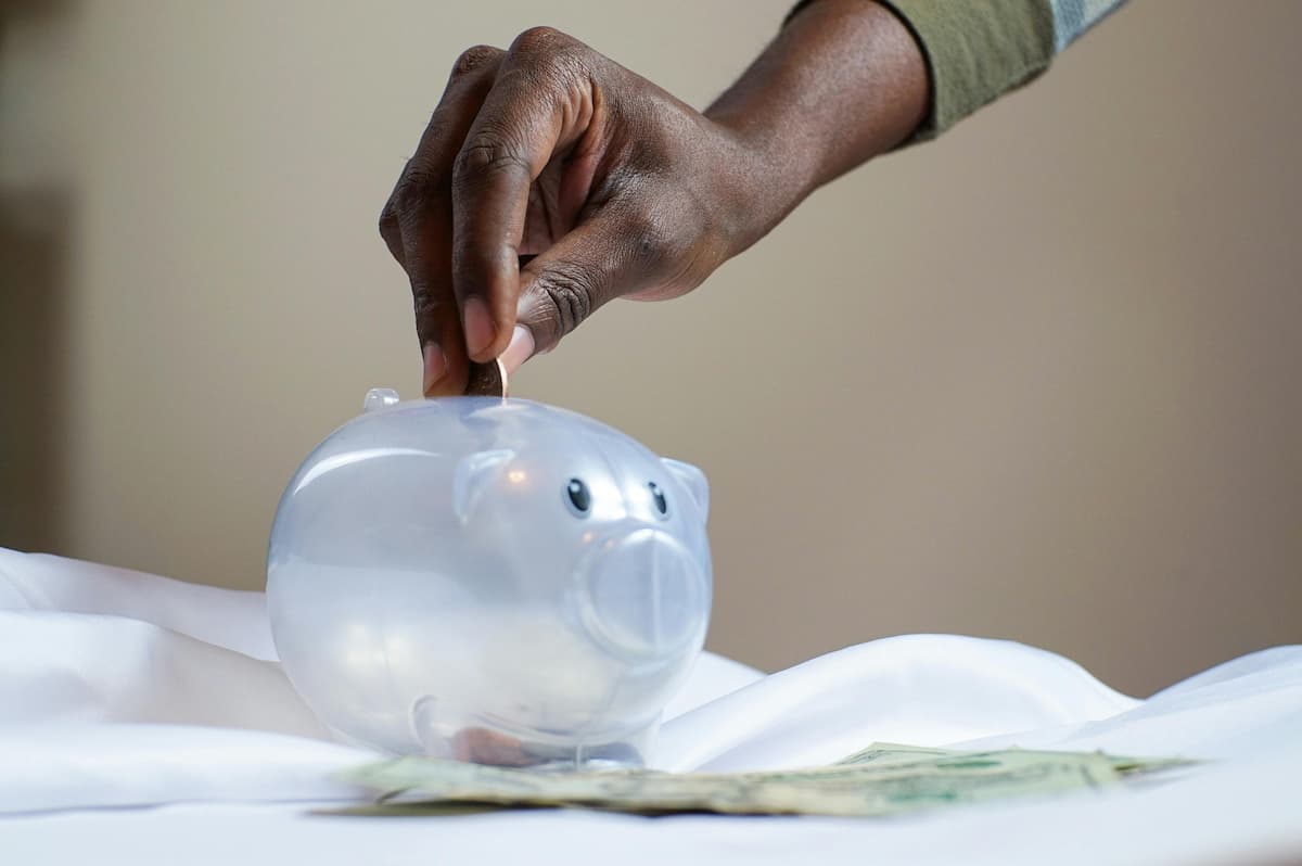 Person putting a coin in a piggy bank to signify budgeting and saving money
